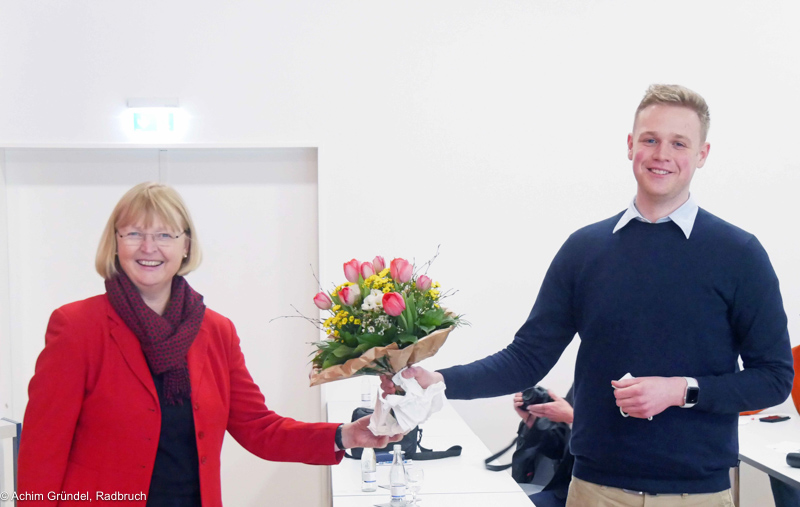 Andrea Schröder-Ehlres überreicht  Jakob Blankenburg einen Blumenstrauß