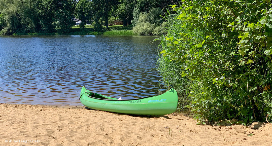 Badestrand mit Sand und Wasser, Kanu